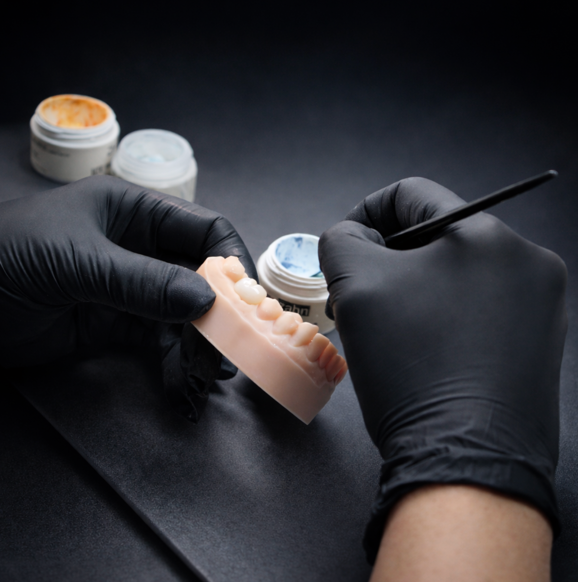 Técnico trabajando con guantes negros en una restauración dental en el laboratorio BDL Benidorm
